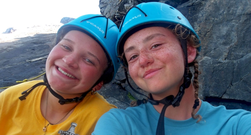 Two people wearing helmets smile for a photo. 